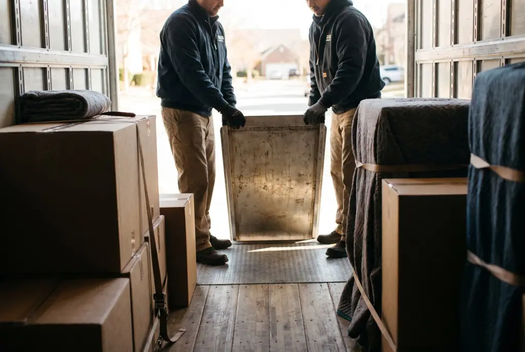 Emergency movers Lubbock crew in matching uniforms efficiently loading wrapped furniture into a clean moving truck at a modern home
