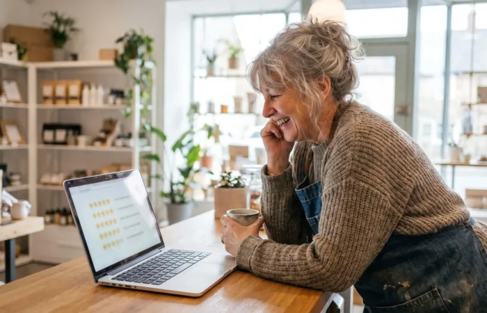 Bright modern Lubbock office with a business owner reading customer reviews on a laptop and phone, screens deliberately blurred with no readable text