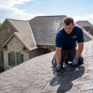 Roof Leak Repair in Lubbock: How to Find and Fix a Leak Fast 11 Roofer tracing a roof leak repair in Lubbock across the shingles of a modern brick home under a clear blue sky