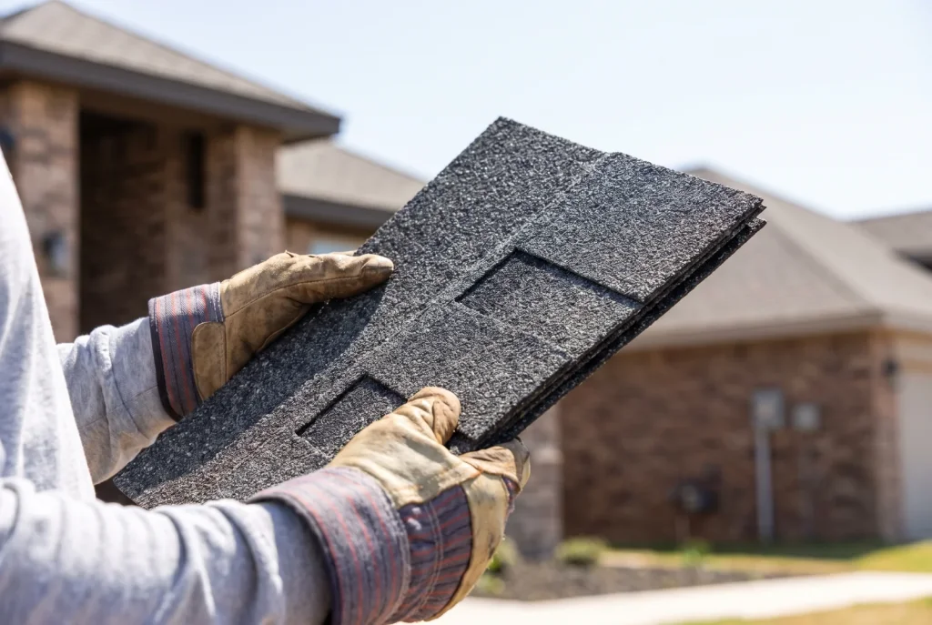 Roofing contractor holding an impact-resistant shingle sample during a Lubbock roof inspection.