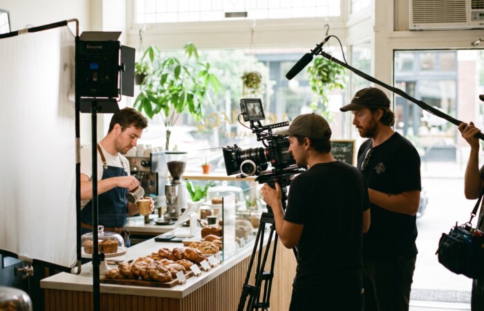 Bright modern Lubbock setting with a marketer filming a short business video on a phone stabilizer, monitor screen deliberately blurred with no readable text